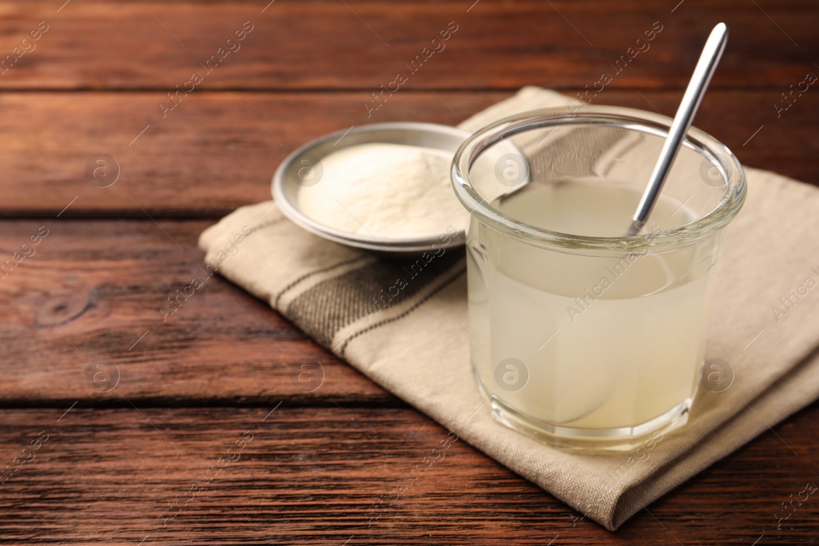 Photo of Glass of agar-agar jelly and bowl with powder on wooden table. Space for text