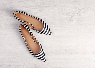 Photo of Pair of female shoes on wooden background, top view