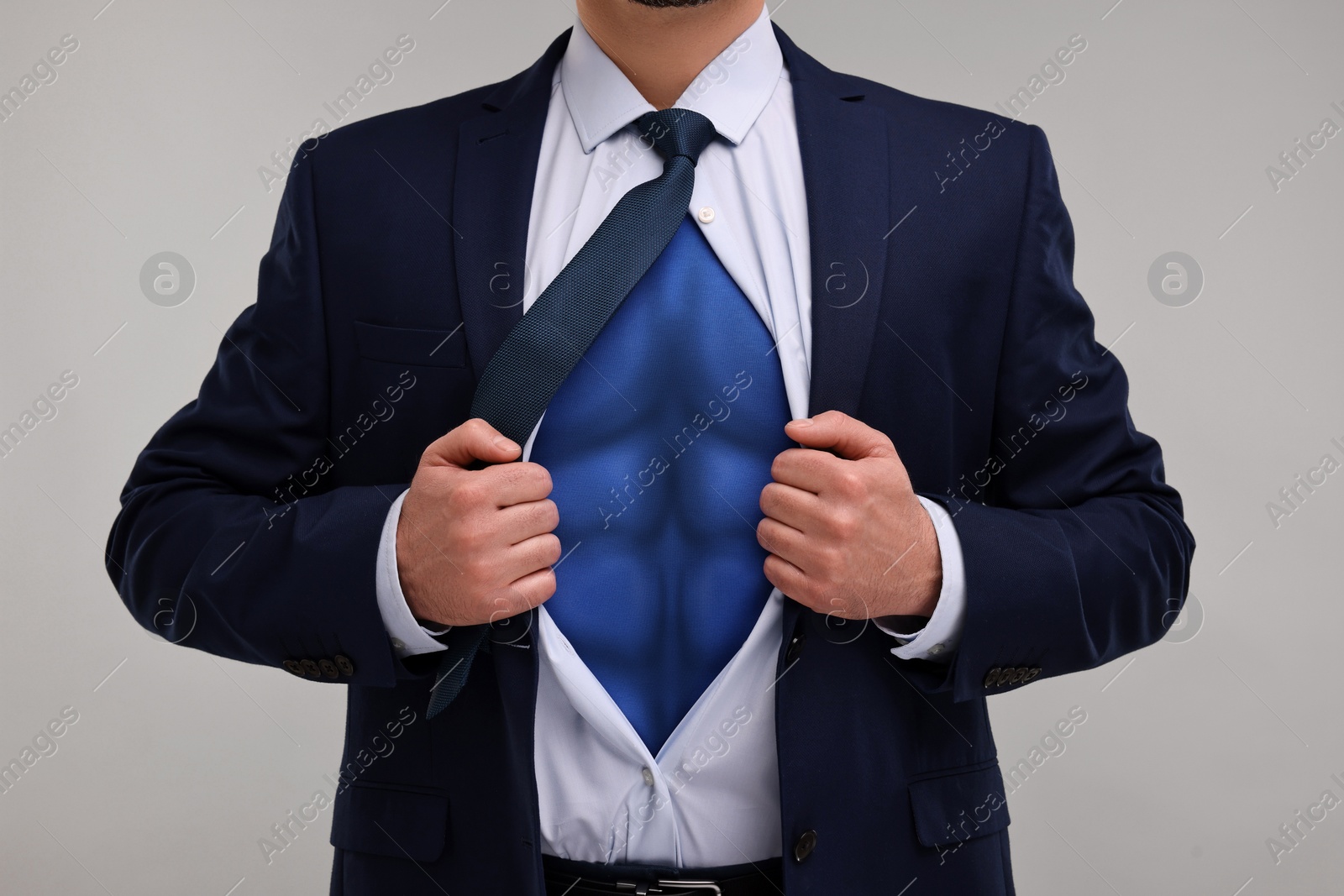 Image of Businessman wearing superhero costume under suit on light grey background, closeup