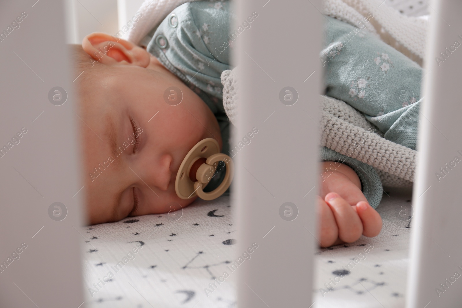 Photo of Adorable baby with pacifier peacefully sleeping in crib