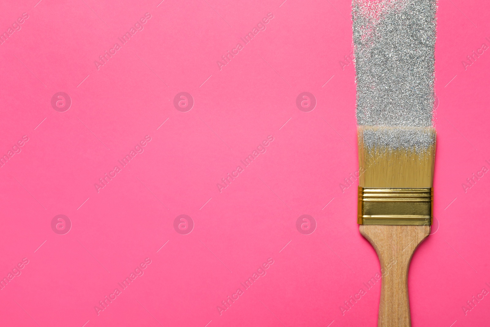 Photo of Brush painting with silver glitter on pink background, top view. Space for text. Creative concept