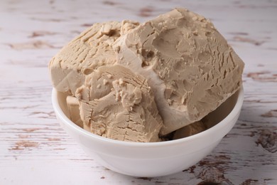 Photo of Compressed yeast on white wooden table, closeup