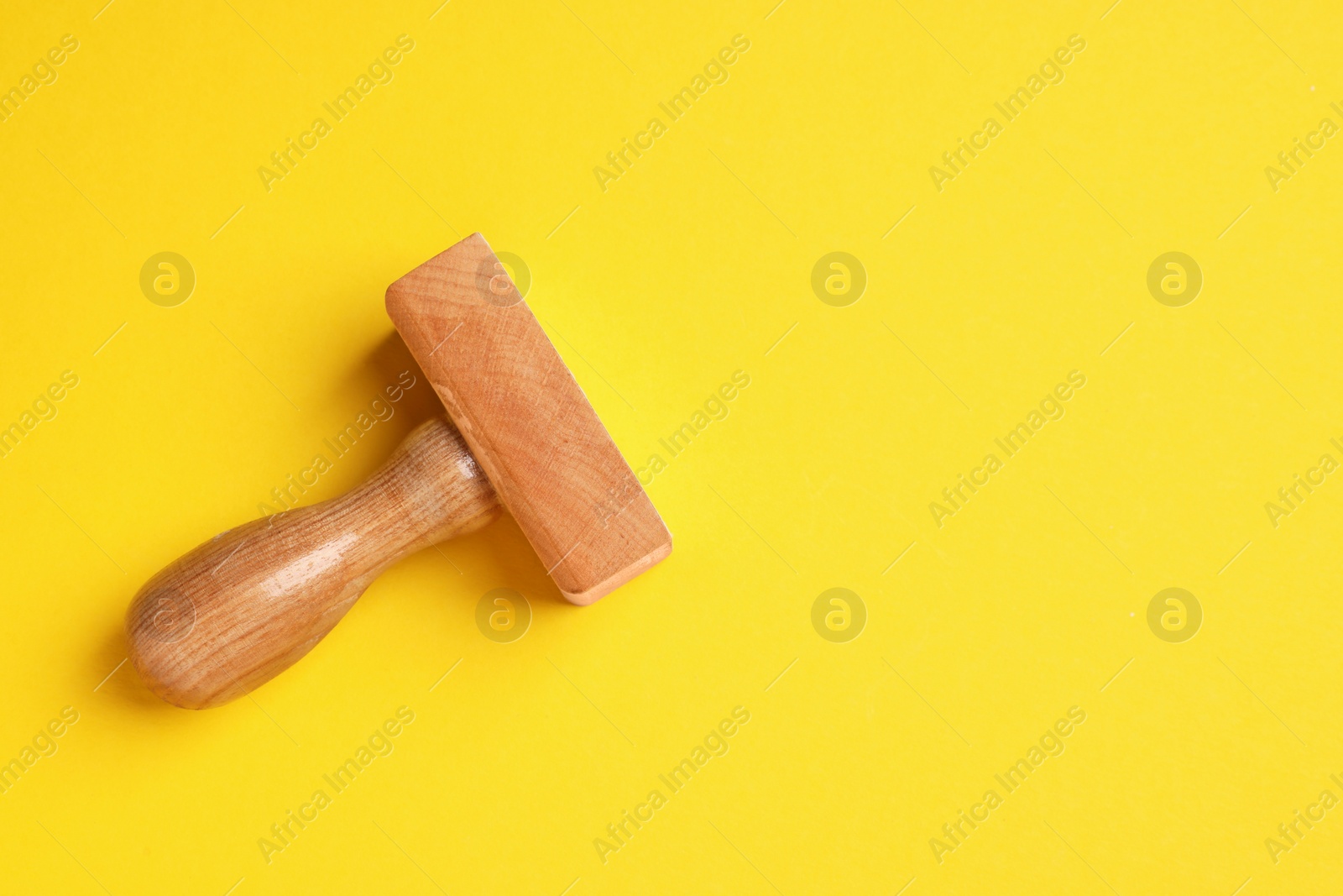 Photo of One wooden stamp tool on yellow background, top view. Space for text