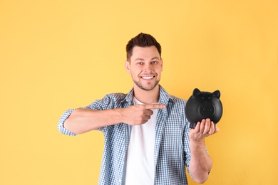 Photo of Man with piggy bank on color background