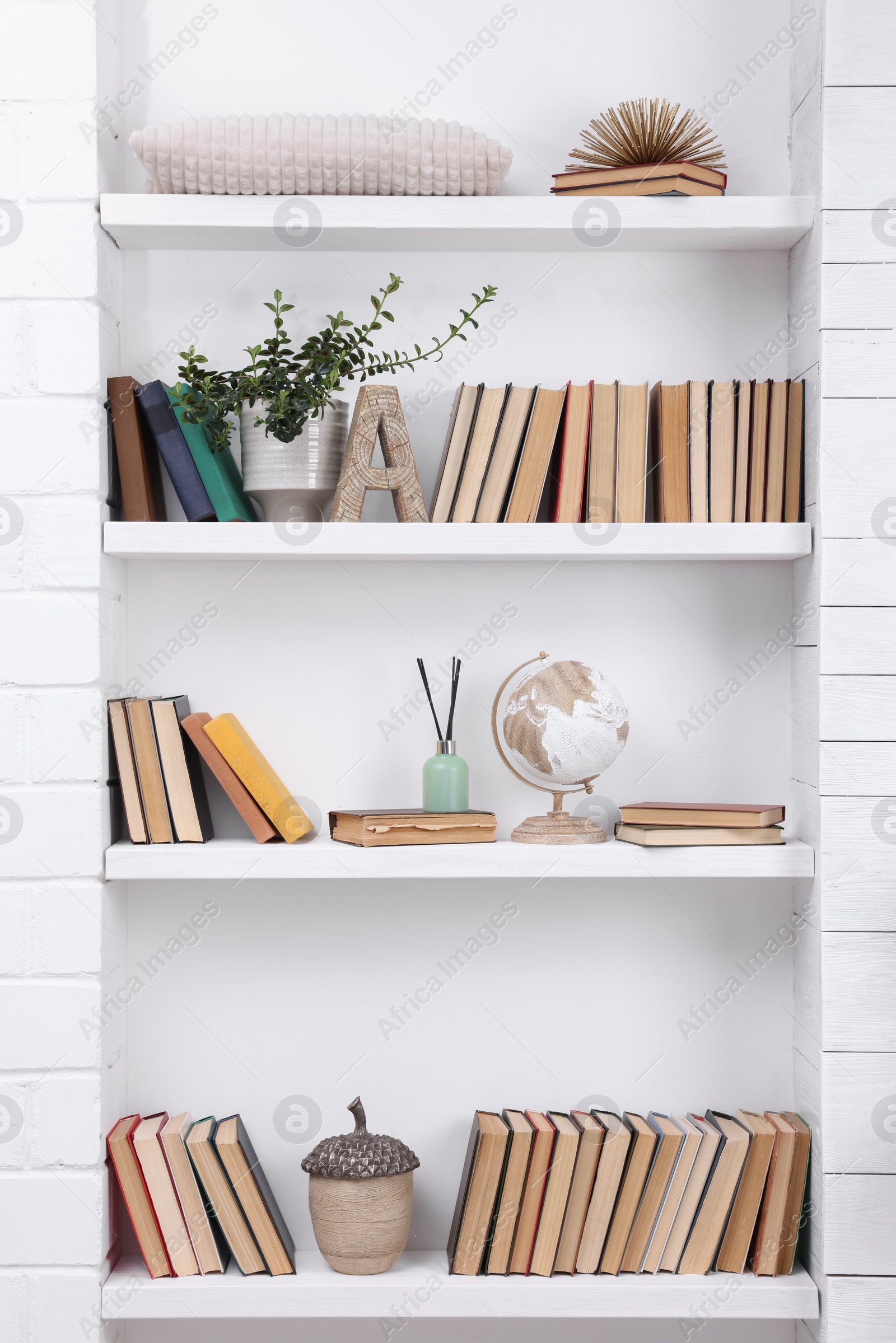 Photo of Collection of books and decor elements on shelves indoors