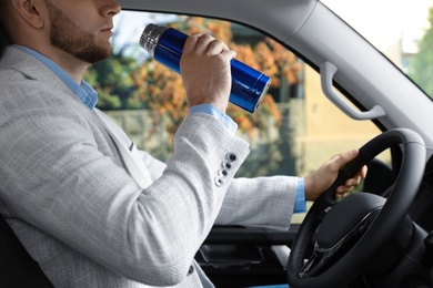 Photo of Man with thermos driving car, closeup view