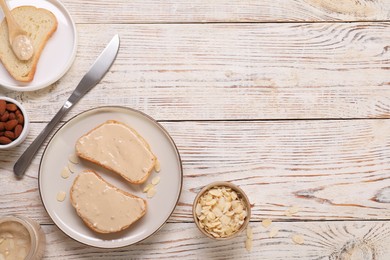 Photo of Toasts with tasty nut butter and almonds on light wooden table, flat lay. Space for text