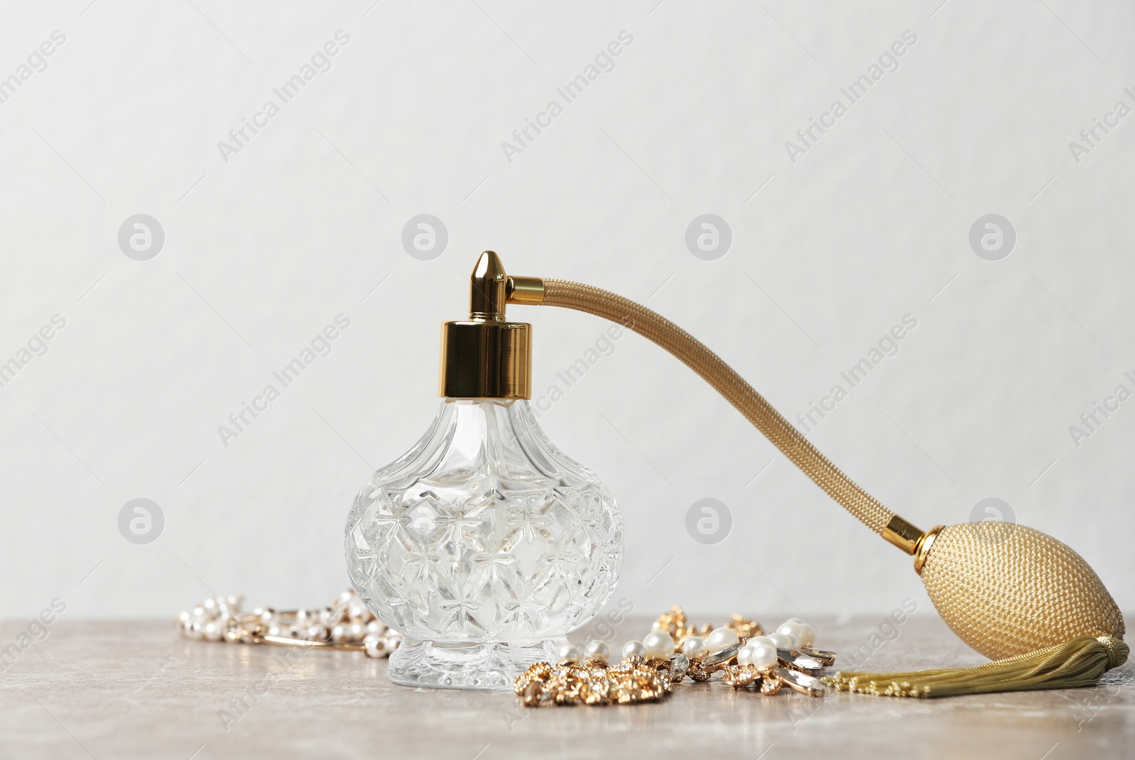 Photo of Perfume bottle and jewellery on table against white background