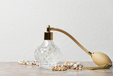 Perfume bottle and jewellery on table against white background