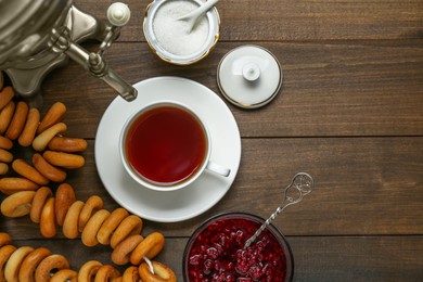 Photo of Flat lay composition with delicious ring shaped Sushki (dry bagels) and cup of tea on wooden table, space for text