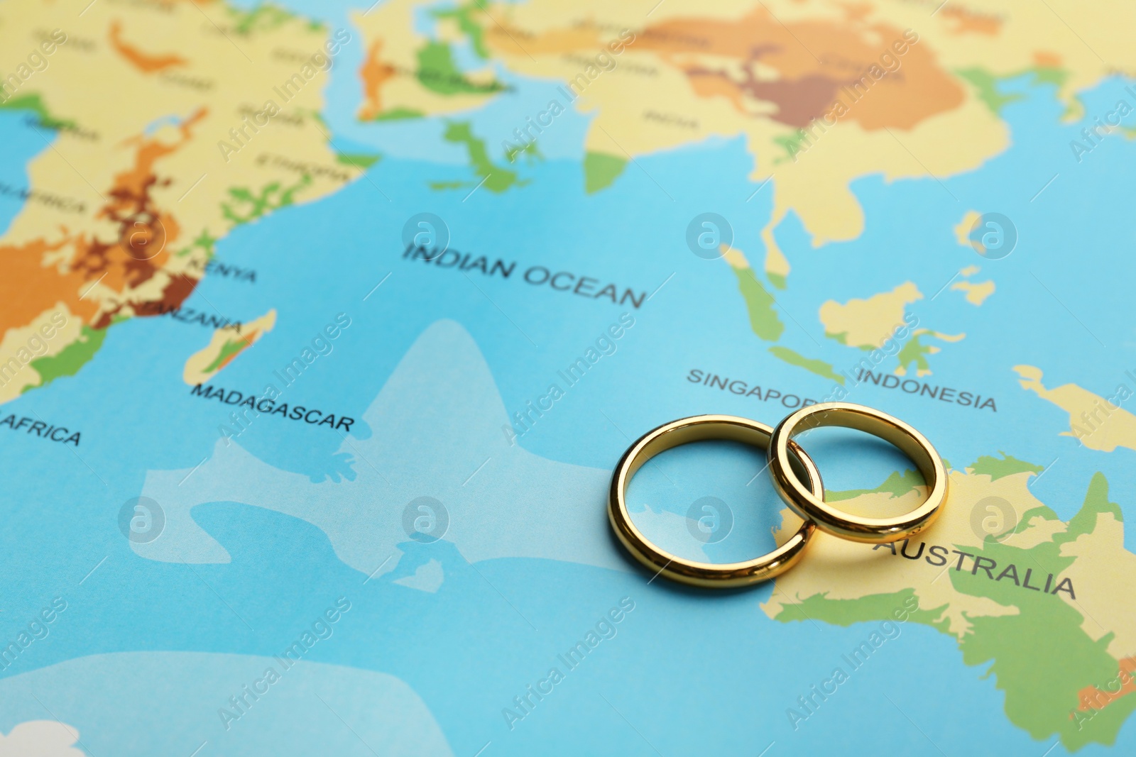 Photo of Honeymoon concept. Two golden rings on world map, closeup. Space for text