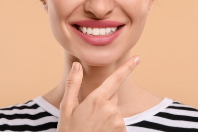 Photo of Woman with clean teeth smiling on beige background, closeup