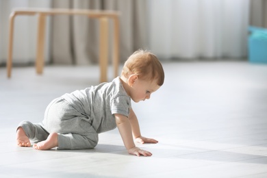 Cute baby crawling on floor at home