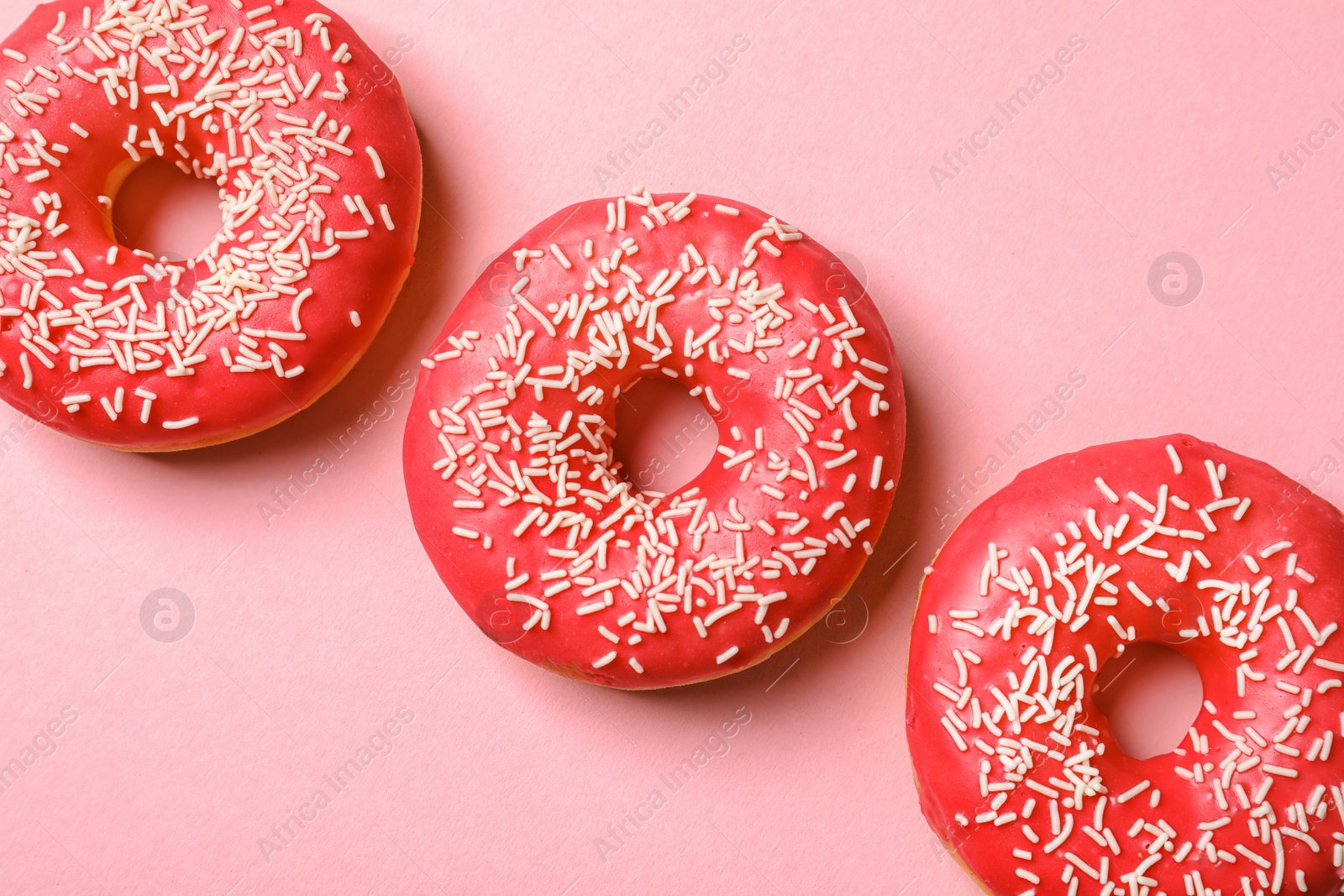 Photo of Delicious glazed doughnuts on color background, top view