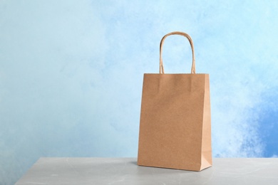 Photo of Mockup of paper shopping bag on table against color background