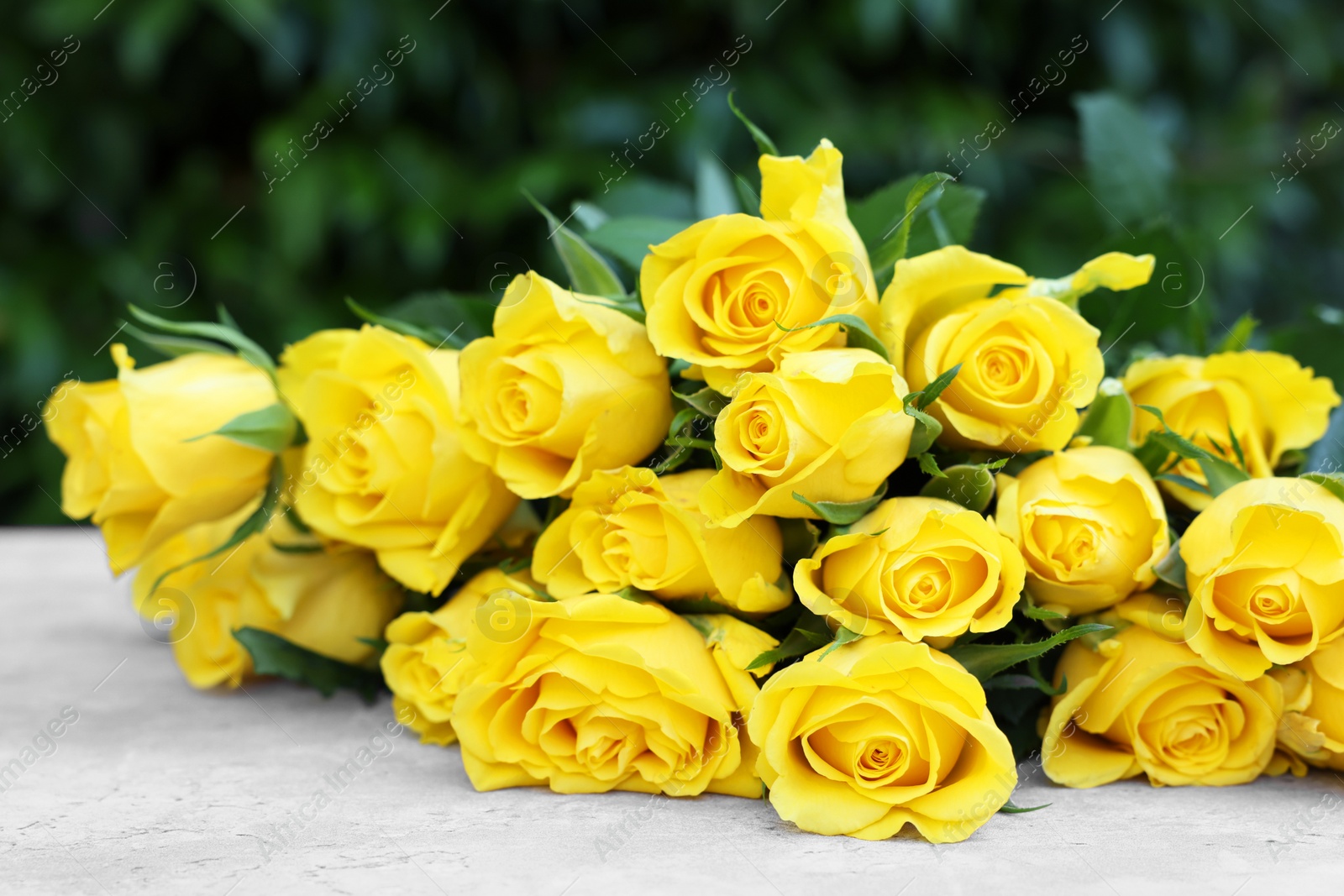 Photo of Beautiful bouquet of yellow roses on light table outdoors, closeup