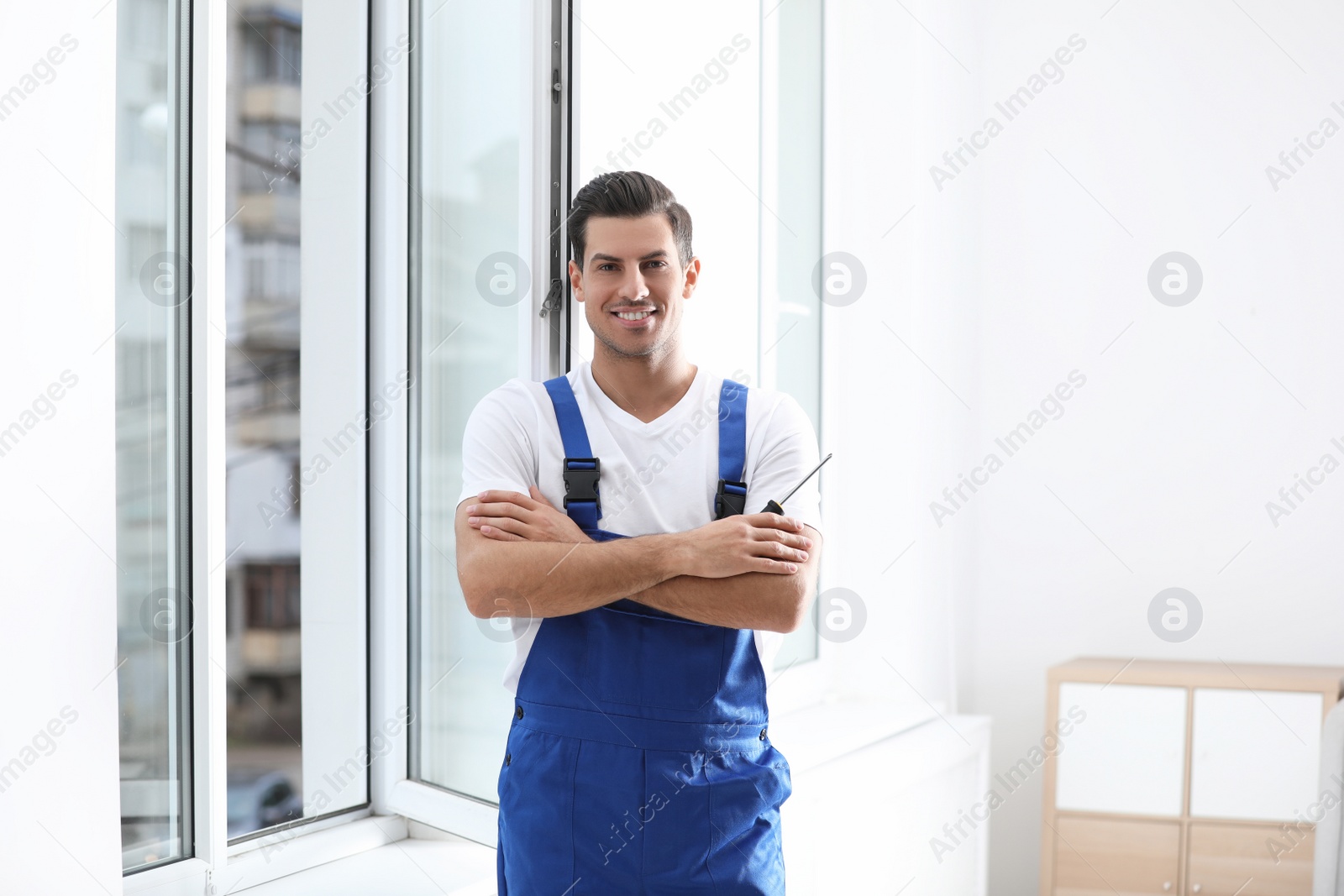 Photo of Repairman with screwdriver near plastic window indoors