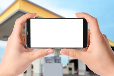 Image of Man paying for refueling via smartphone at gas station, closeup. Device with empty screen