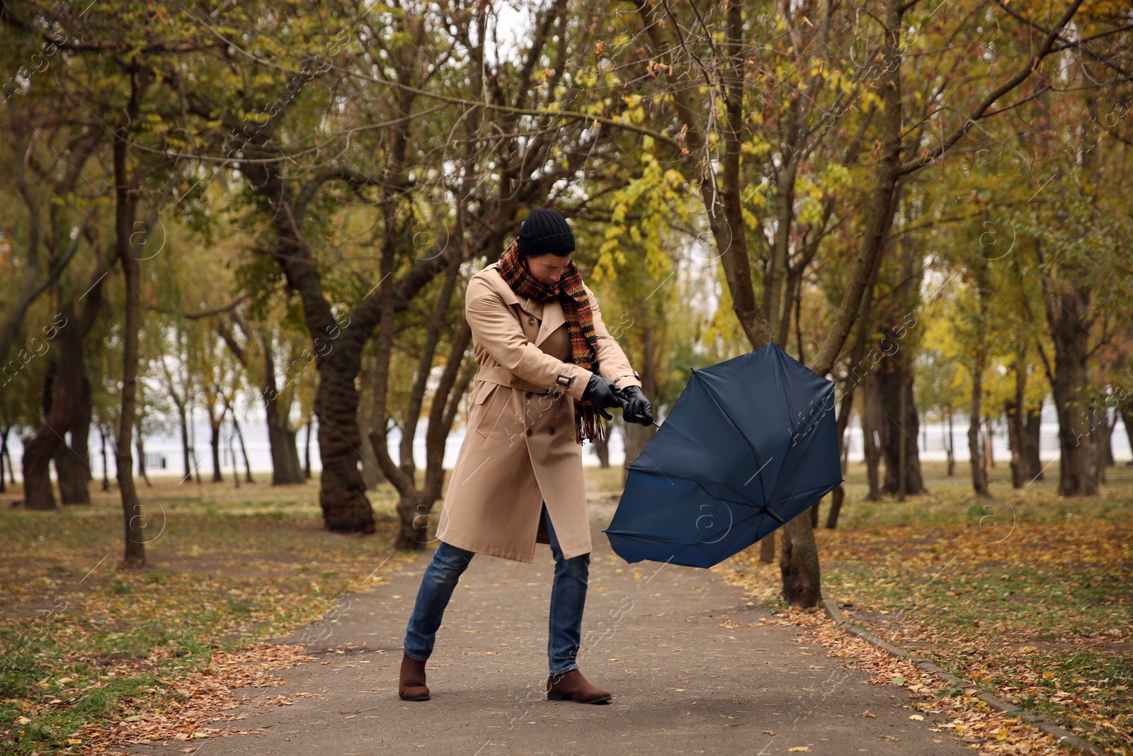 Photo of Man with blue umbrella caught in gust of wind outdoors