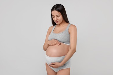 Photo of Beautiful pregnant woman in comfortable maternity underwear on grey background
