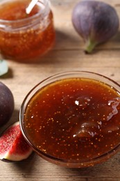 Photo of Bowl with tasty sweet jam and fresh figs on wooden table, closeup