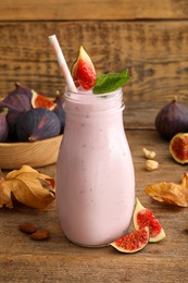Photo of Delicious fig smoothie in glass bottle on wooden table