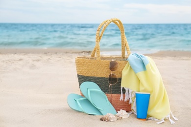 Photo of Different stylish beach objects and seashells on sand near sea