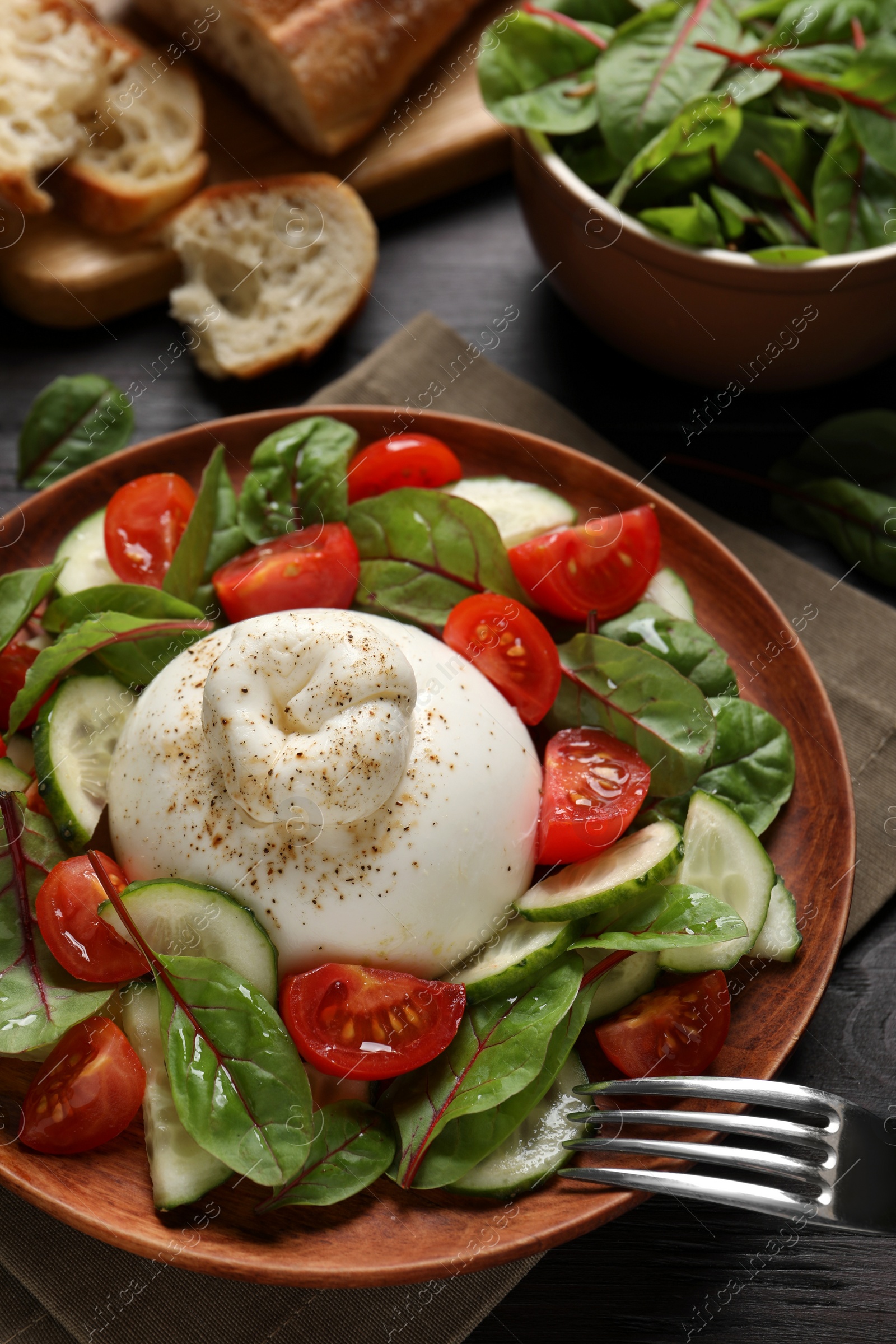 Photo of Delicious burrata salad served on wooden table, above view