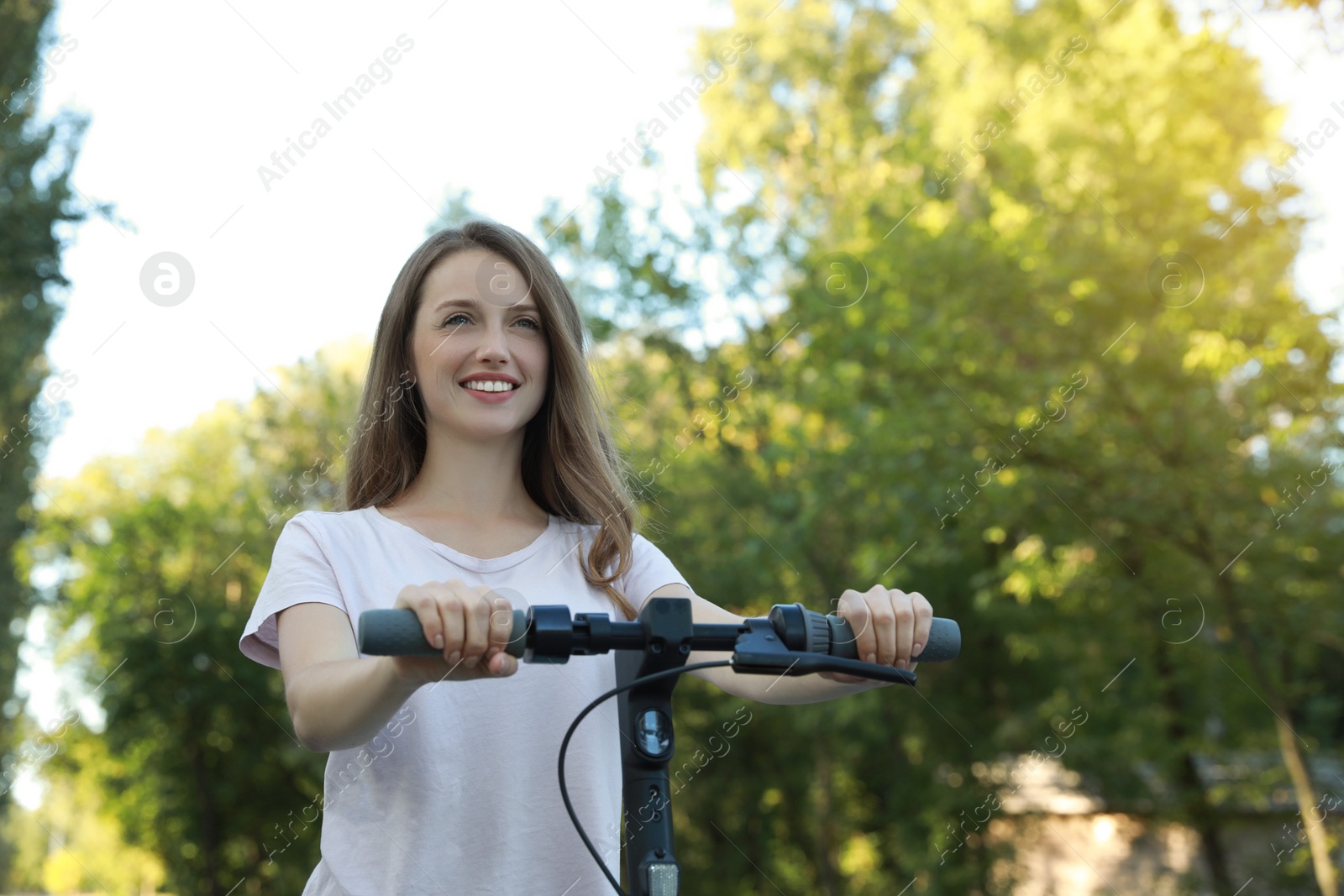 Photo of Happy woman riding modern electric kick scooter in park