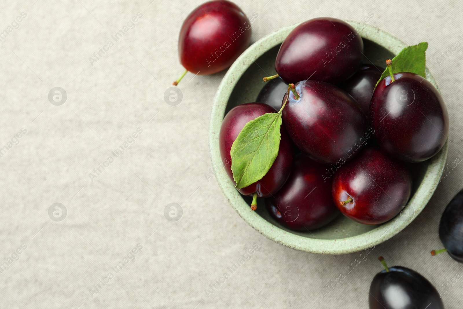 Photo of Tasty ripe plums on light fabric, flat lay. Space for text