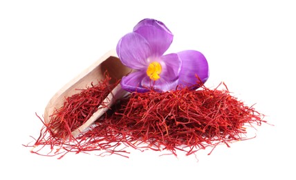 Pile of dried saffron, crocus flower and wooden scoop on white background