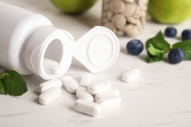 Bottle with vitamin pills, blueberries and mint on light table,m closeup