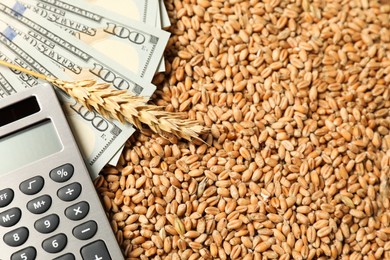 Photo of Dollar banknotes, calculator, wheat ear and grains on table, closeup. Agricultural business