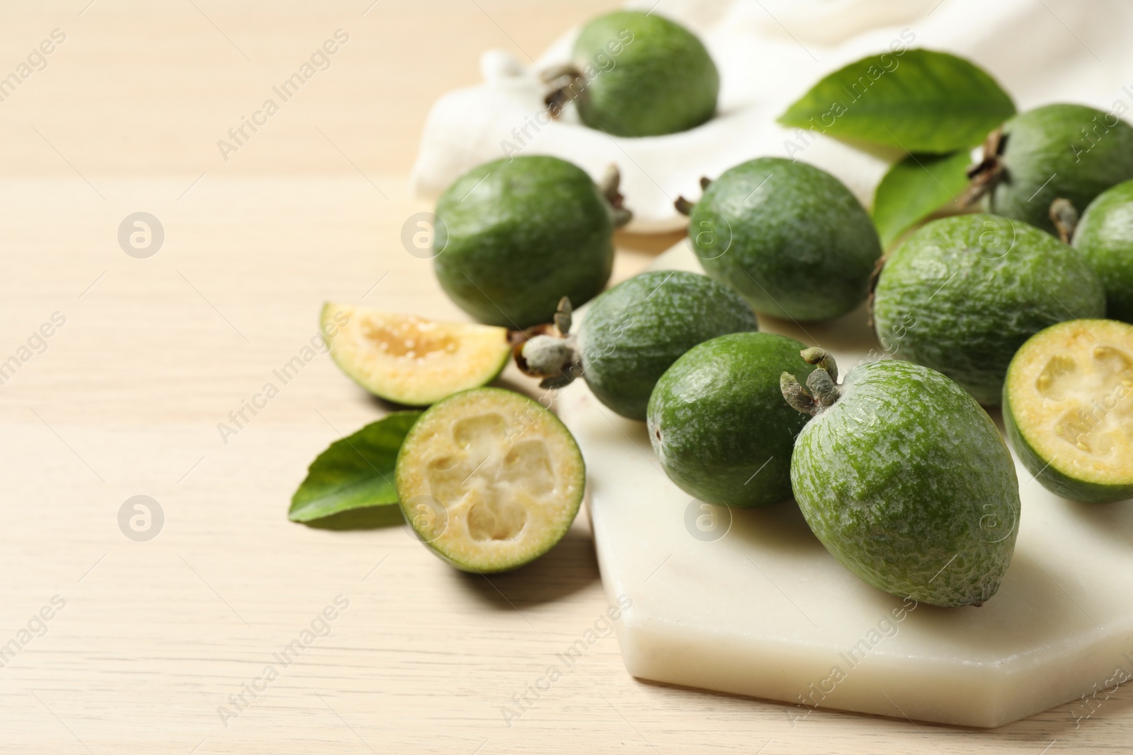 Photo of Fresh green feijoa fruits on wooden table, space for text