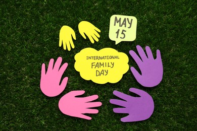 Photo of Card with text Family Day surrounded by paper palms on green grass, flat lay