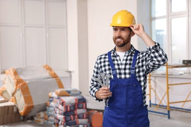 Photo of Professional builder in uniform with tools indoors