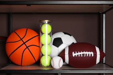 Photo of Different sport balls on shelf near brown wall