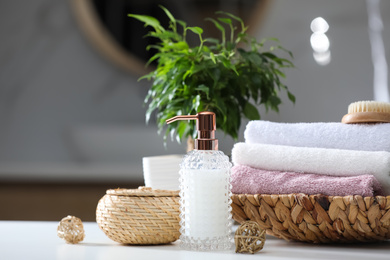 Soap dispenser, towels and brush on white table indoors