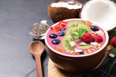 Photo of Delicious acai smoothie with granola and fruits served on black table, closeup. Space for text