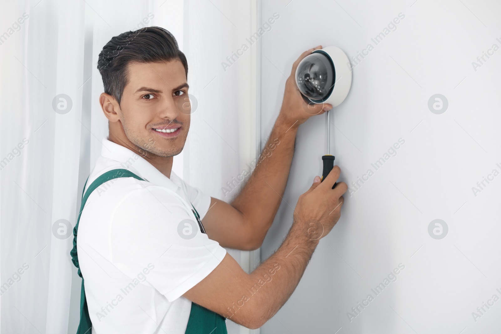 Photo of Technician installing CCTV camera on wall indoors