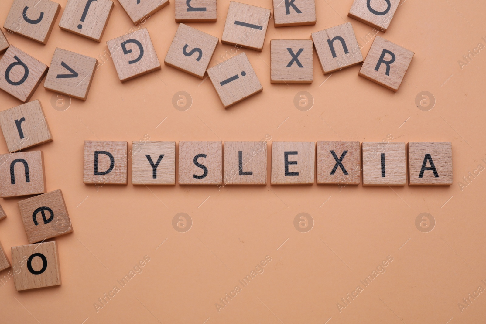 Photo of Wooden cubes with word Dyslexia on pale orange background, flat lay