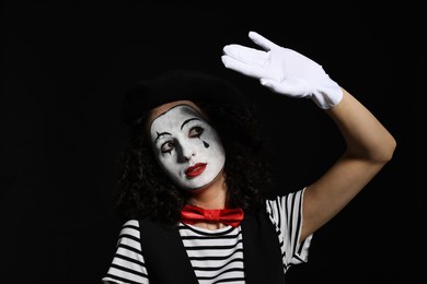 Young woman in mime costume posing on black background