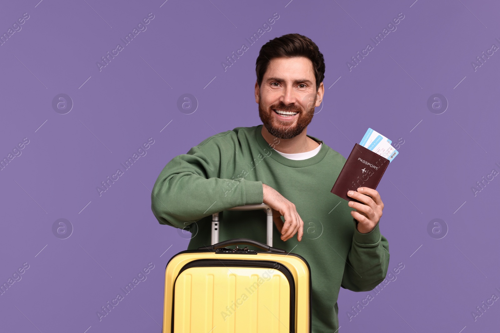 Photo of Smiling man with passport, tickets and suitcase on purple background. Space for text