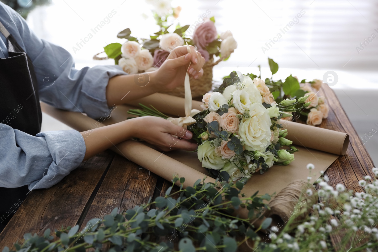 Photo of Florist making beautiful wedding bouquet at wooden table, closeup