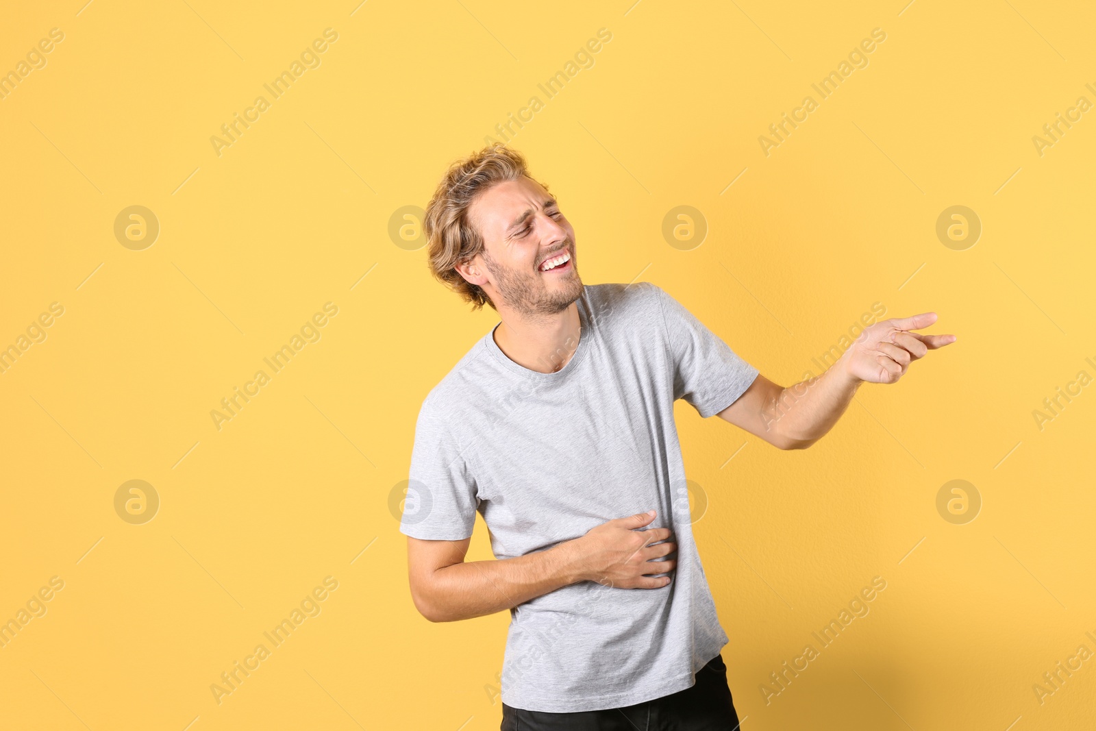 Photo of Handsome young man laughing on color background