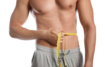 Photo of Young man with slim body using measuring tape on white background, closeup view