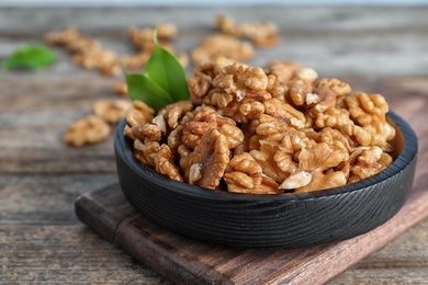 Plate with tasty walnuts on wooden table