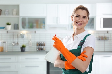 Photo of Portrait of young woman with sprayer in kitchen. Cleaning service