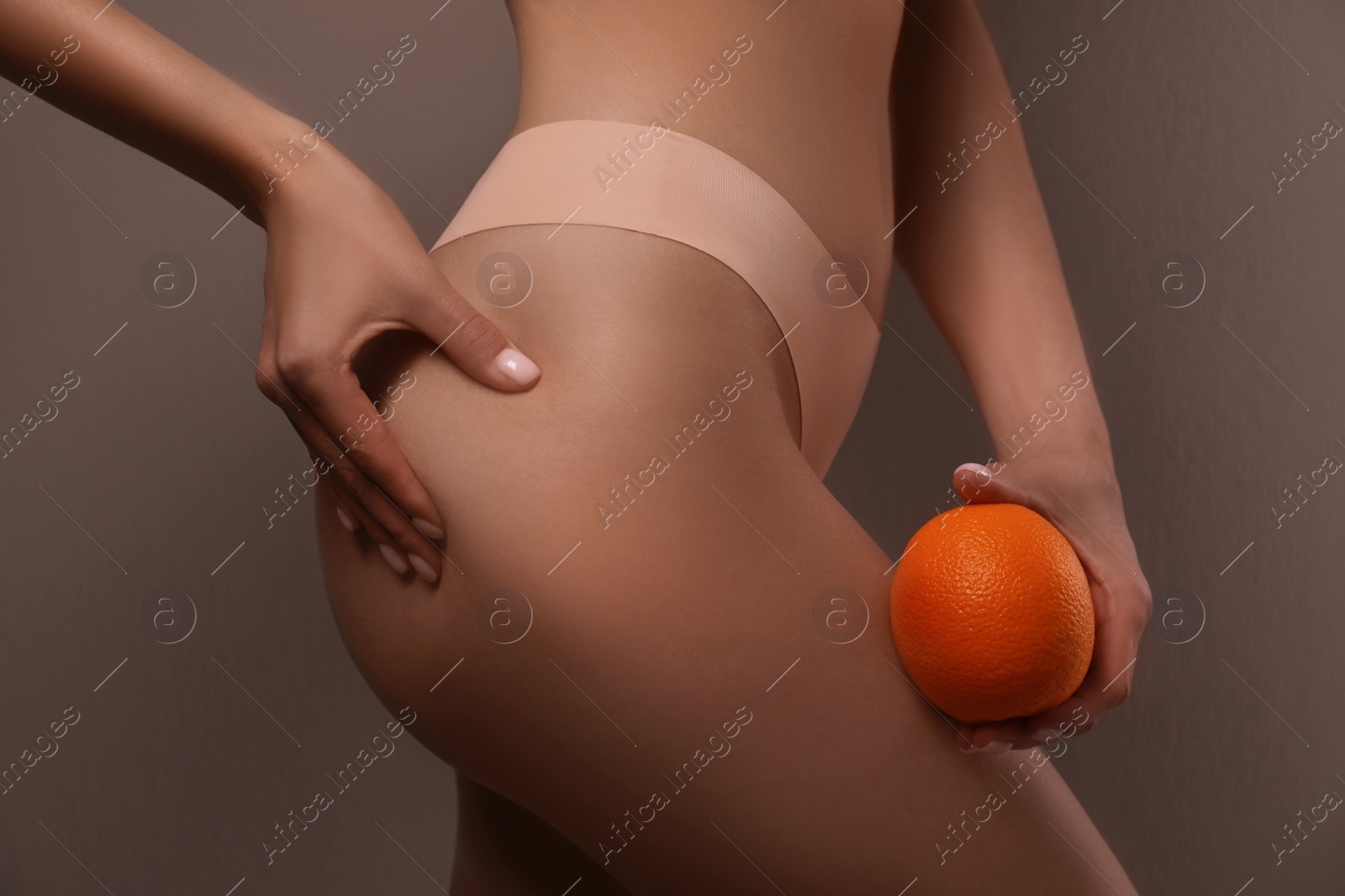 Photo of Closeup view of slim woman in underwear with orange on beige background. Cellulite problem concept