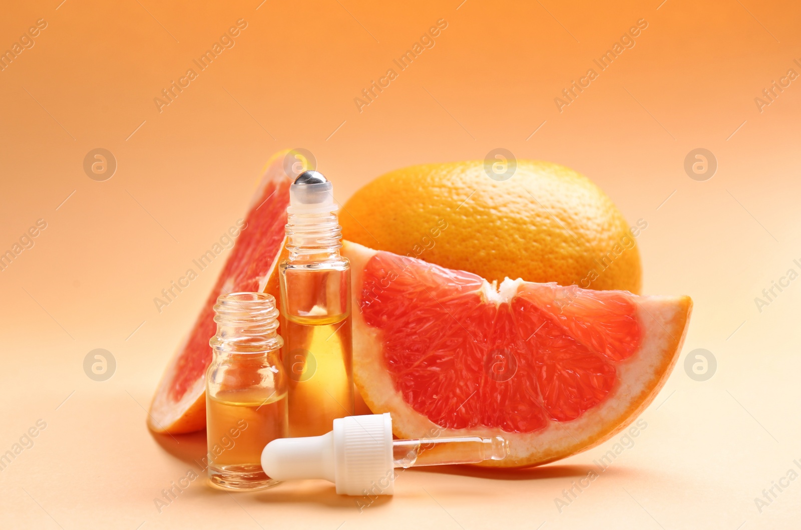 Photo of Bottles of essential oil and fresh grapefruits on color background